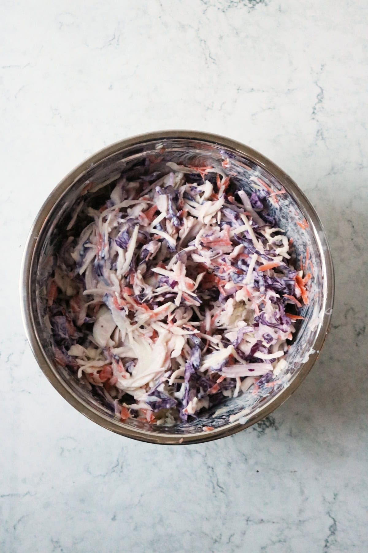 A large metal mixing bowl filled with Vegan Kohlrabi Slaw