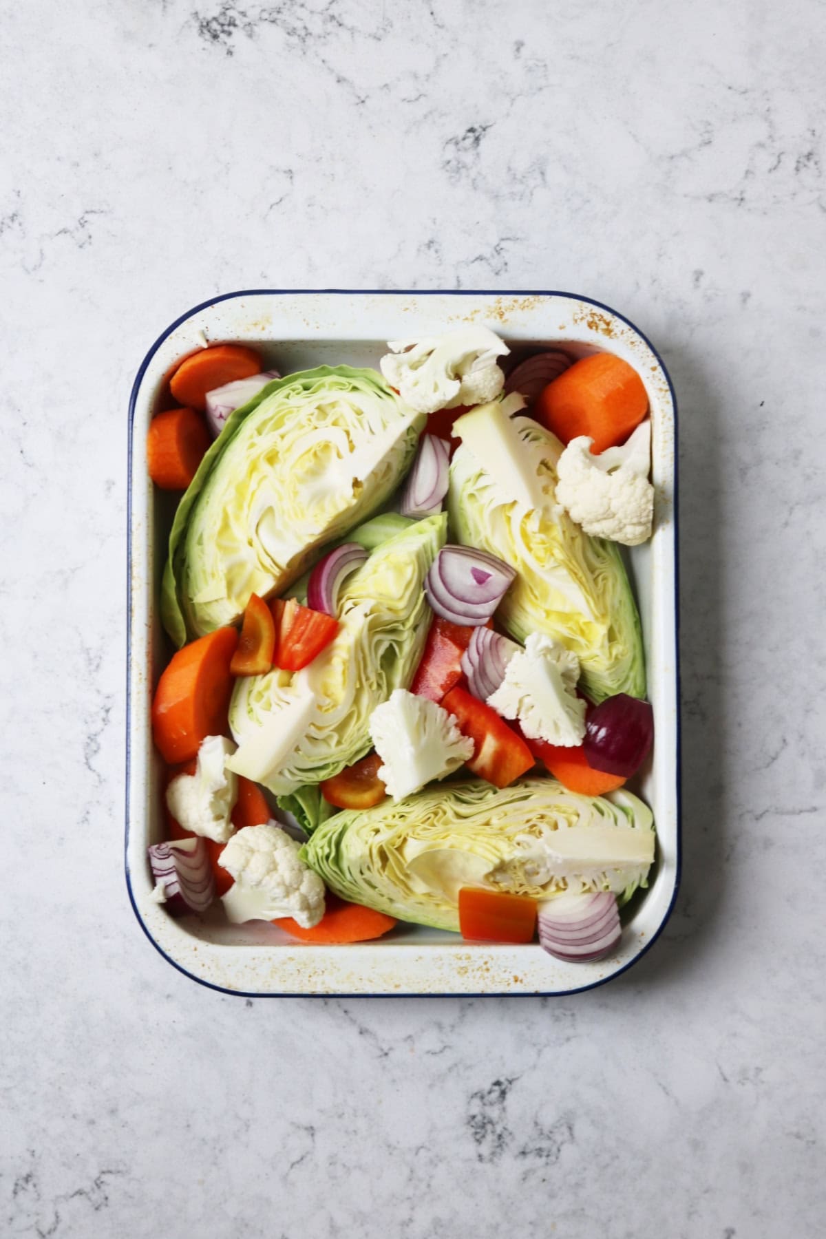 Cabbage, carrot, red onion, red peppers and cualiflower arranged in an enamel roasting tin for Vegan Gochujang Vegetable Traybake