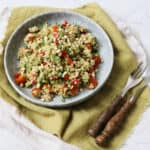 Lemon and Herb Freekeh Salad served on a pale blue plate on top of a green napkin with wooden handled knife and fork