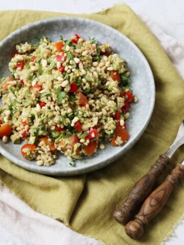 Lemon and Herb Freekeh Salad served on a pale blue plate on top of a green napkin with wooden handled knife and fork