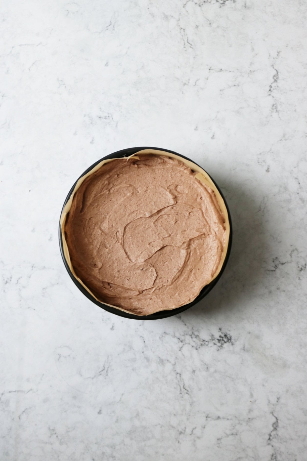 A vegan chocolate cheesecake in a metal tin ready to be chilled in the fridge
