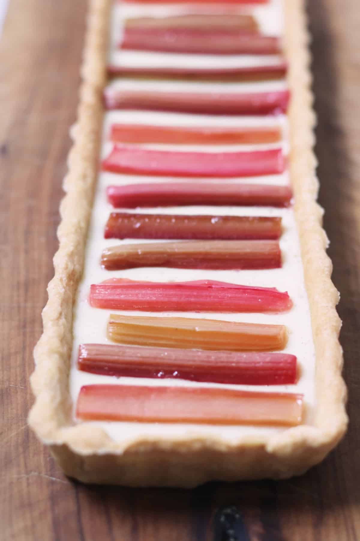 A close up of the roasted rhubarb batons decorating a Vegan Rhubarb and Custard Tart