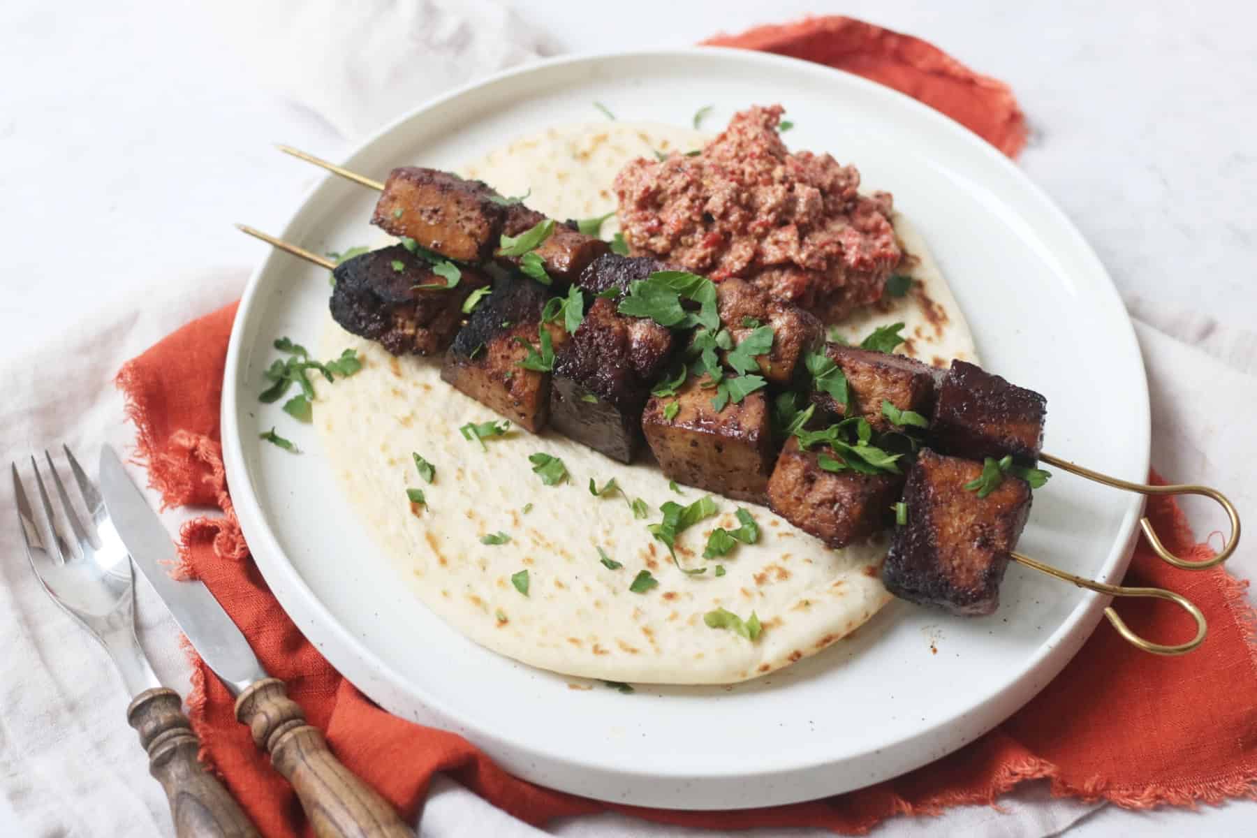 Pomegranate Molasses Tofu Kebabs served with a flatbread and a portion of muhammara (a roasted red pepper and walnut dip)