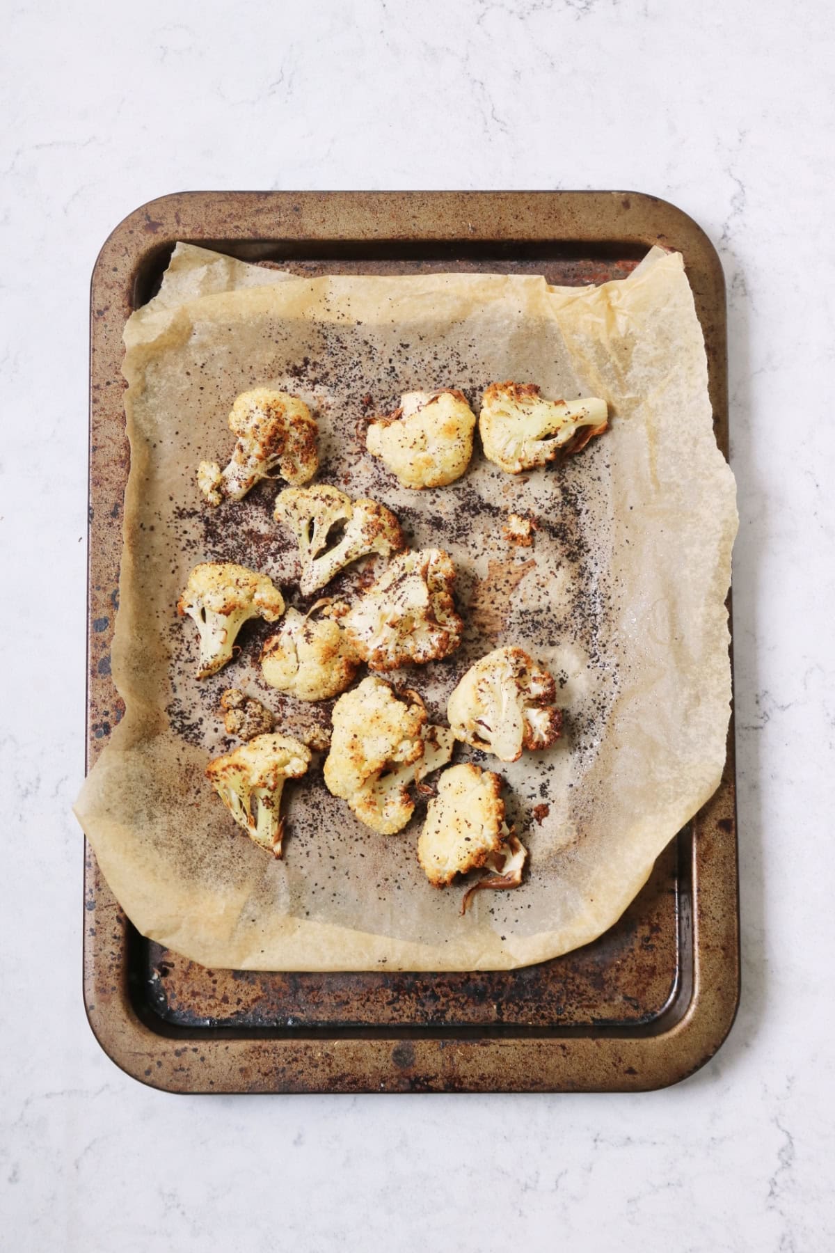 Cauliflower florets coated in sumac on a baking tray lined with baking paper