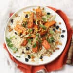 Vegan Warm Moroccan Spiced Couscous with Roasted Carrots on a white plate on top of an orange napkin