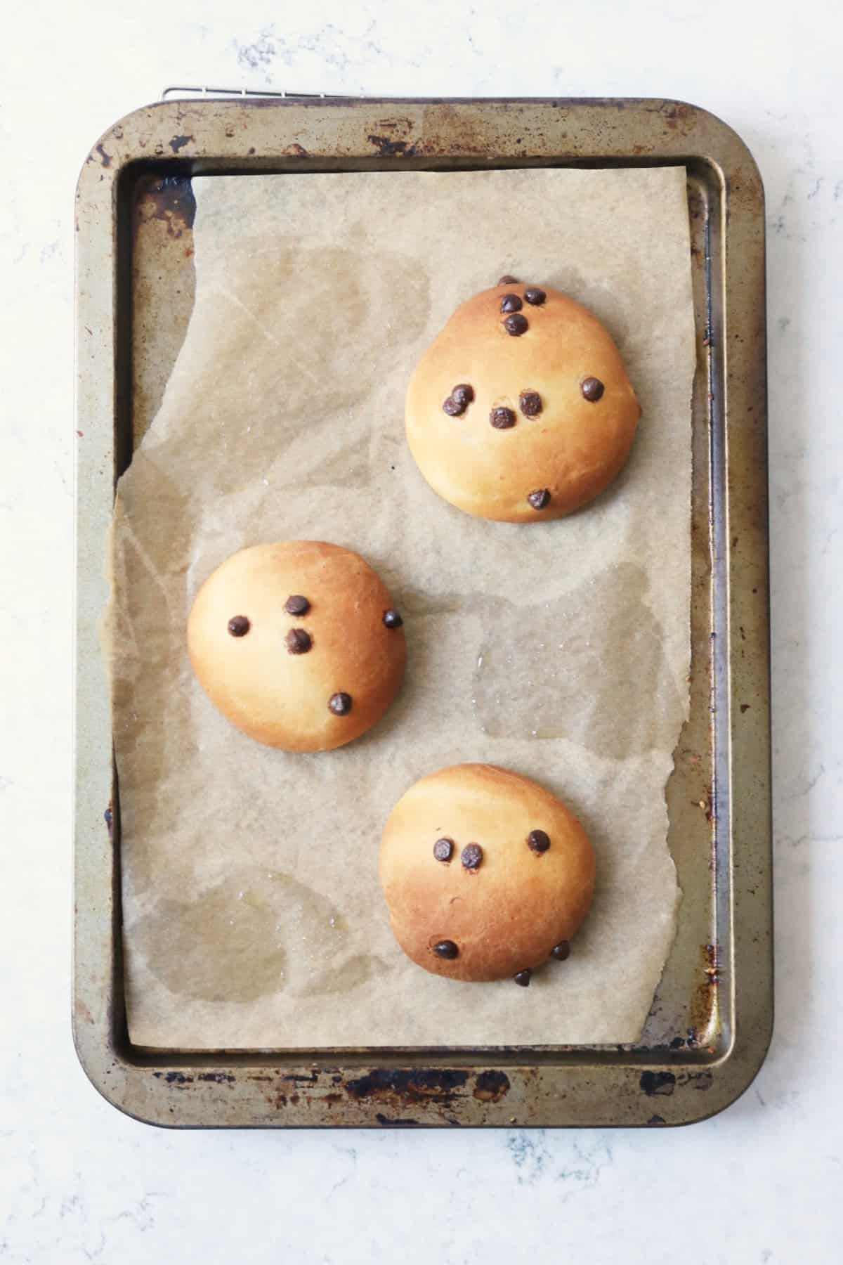 3 baked Vegan Chocolate Maritozzi buns on a baking tray