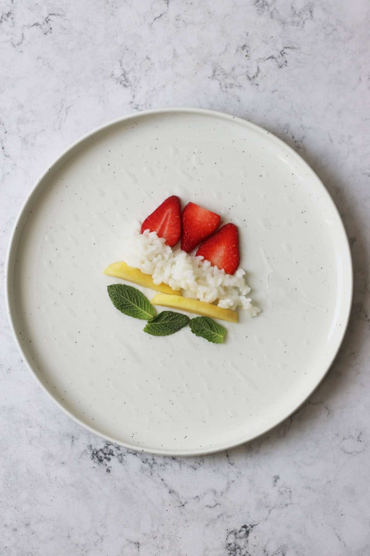 Strawberries, coconut rice, mango and mint leaves in the centre of a rice paper wrapper ready to be rolled into a Sweet Summer Roll