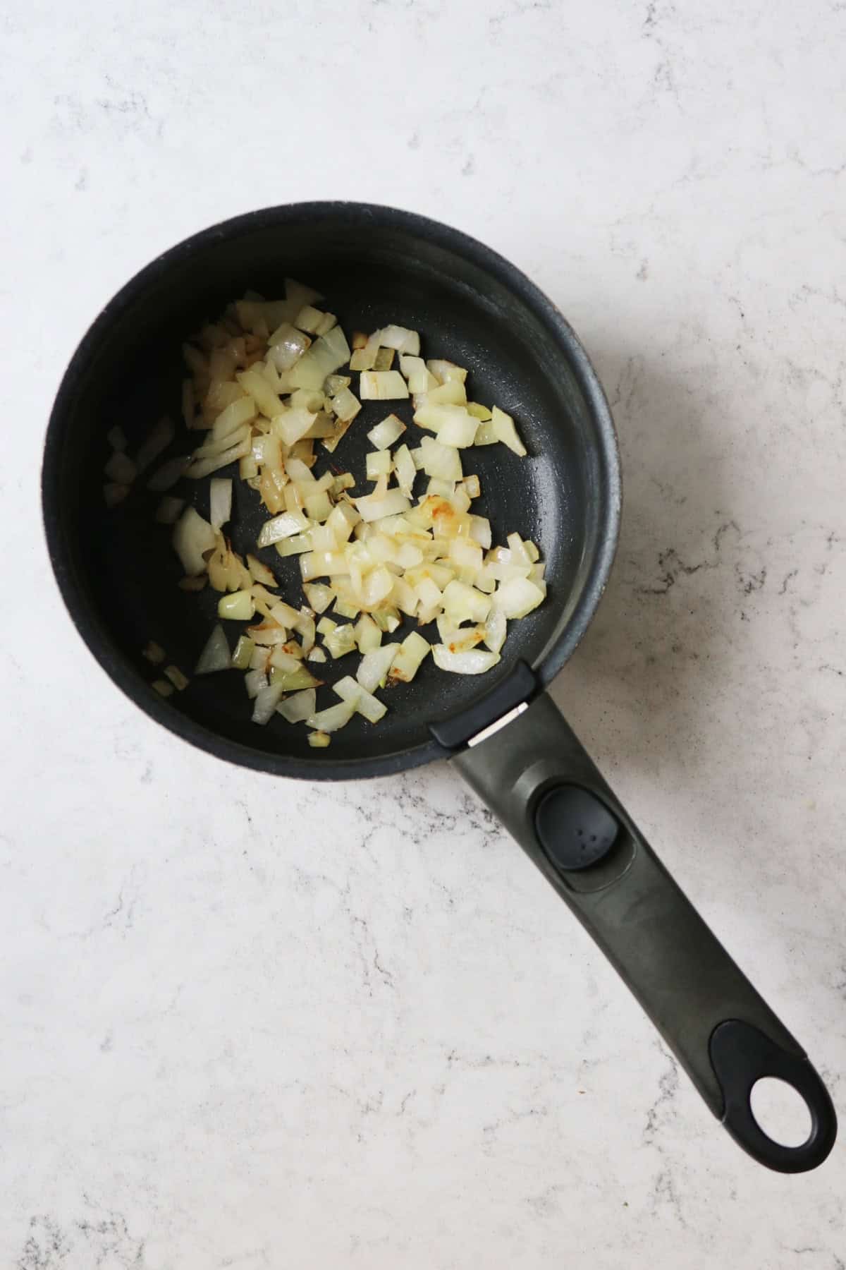 Chopped onion being fried in a saucepan