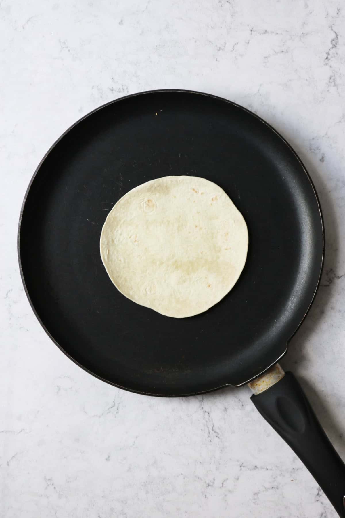 Heating a small flour tortilla in a flat bottomed frying pan