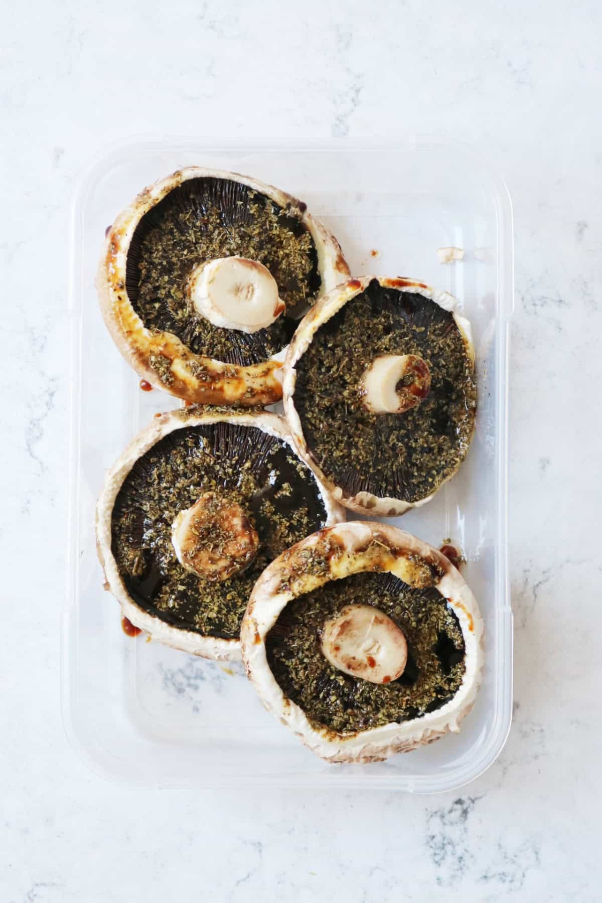 Portobello mushrooms marinating in a tupperware