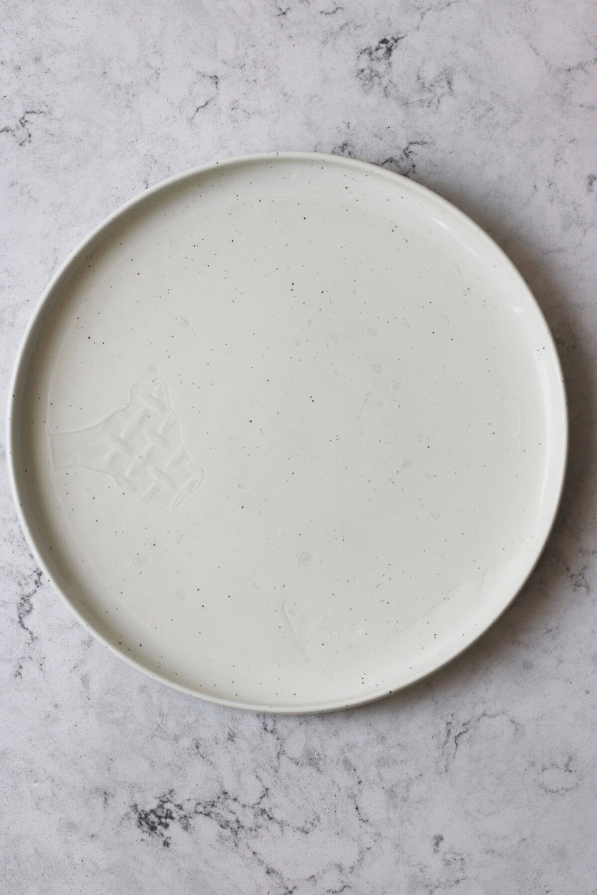 A rice paper wrapper soaking in water on a plate