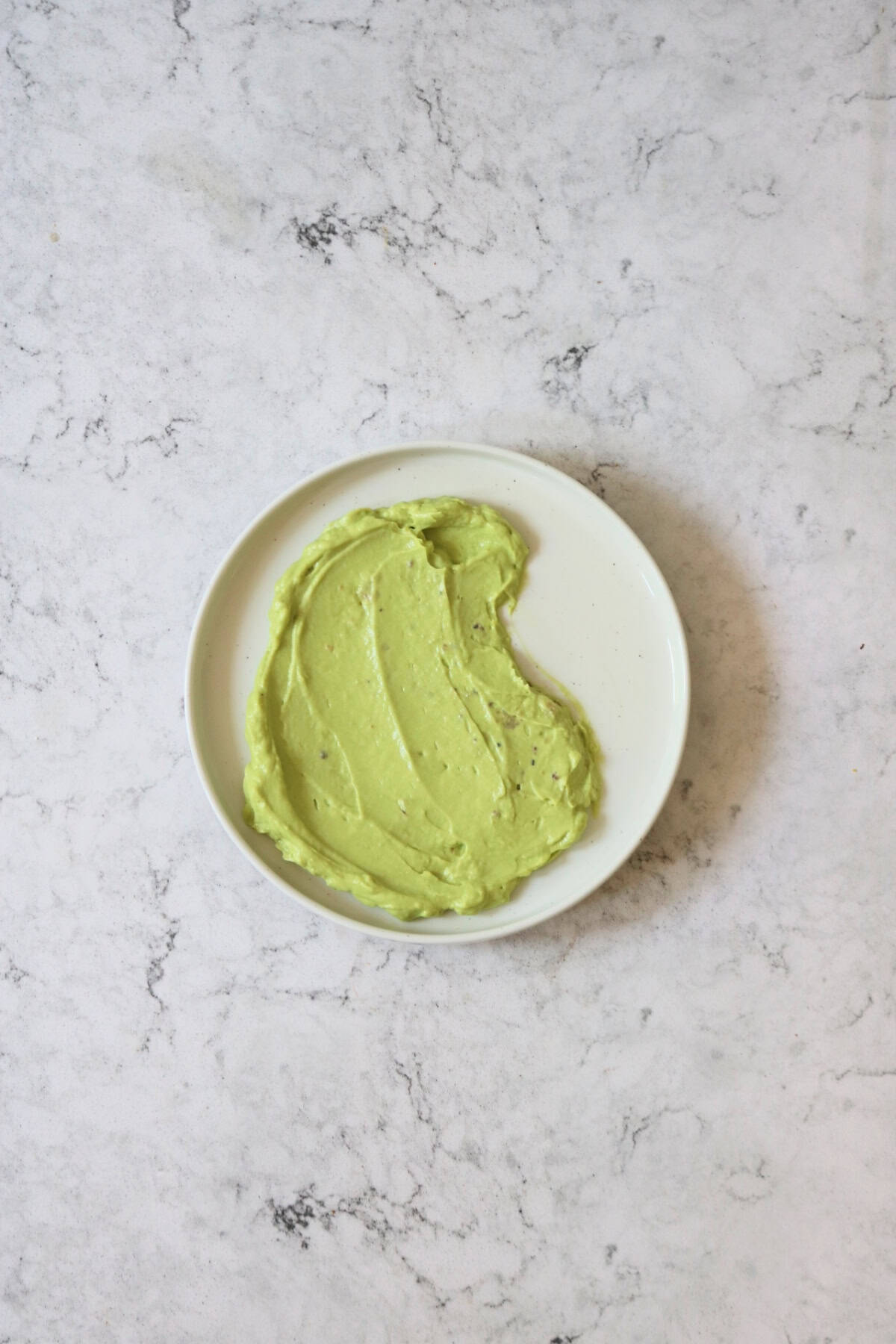 Avocado sauce spread across a white plate