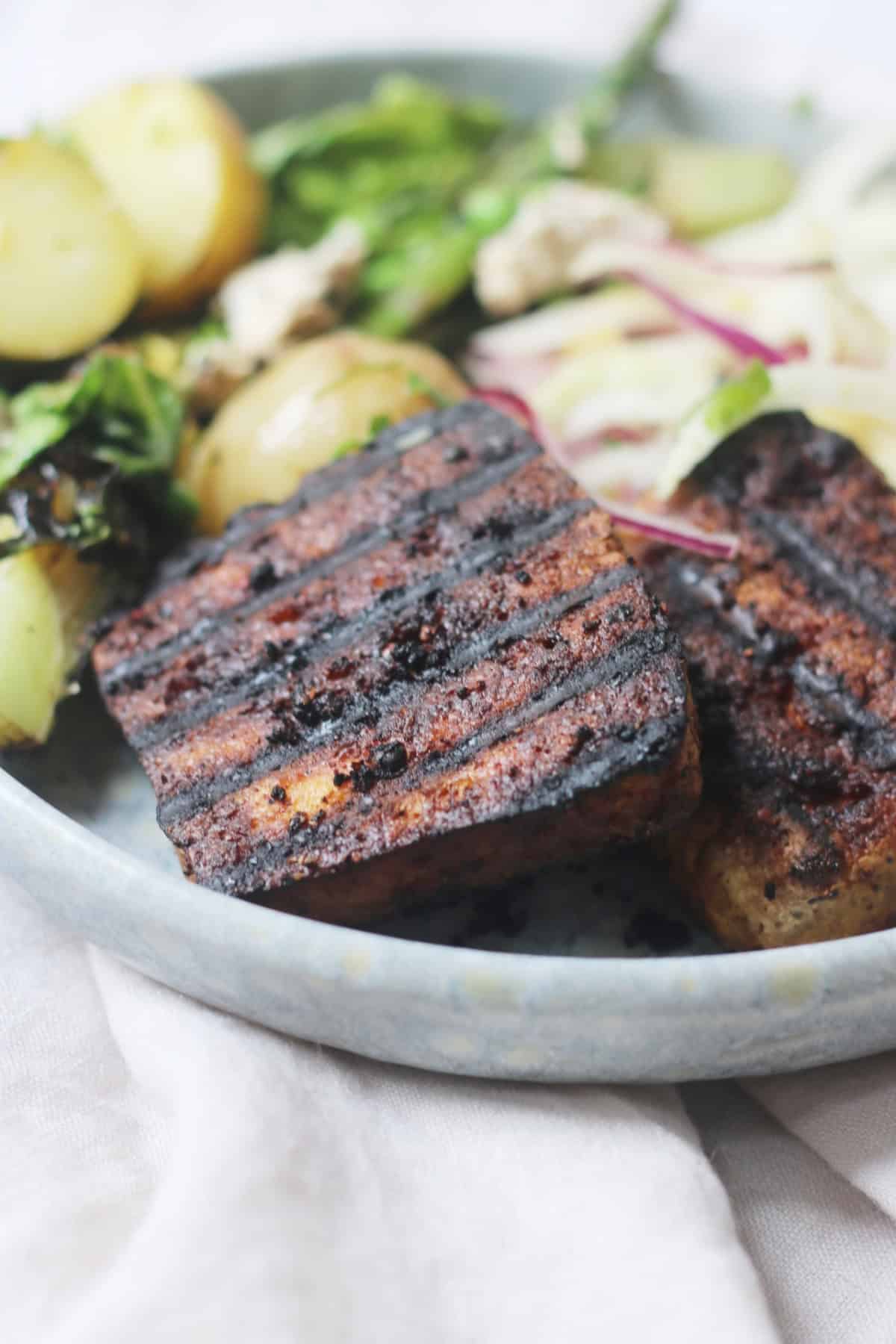 Vegan BBQ Tofu Steaks served on a light blue plate with salad.