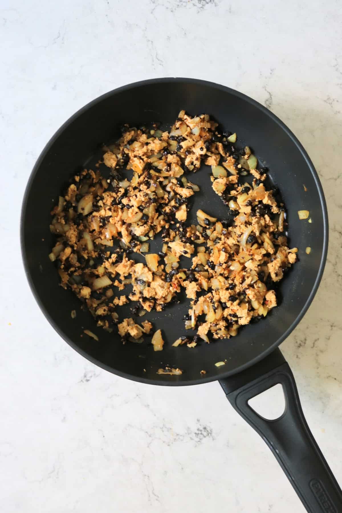 Black bean stuffed tofu filling frying in a large frying pan
