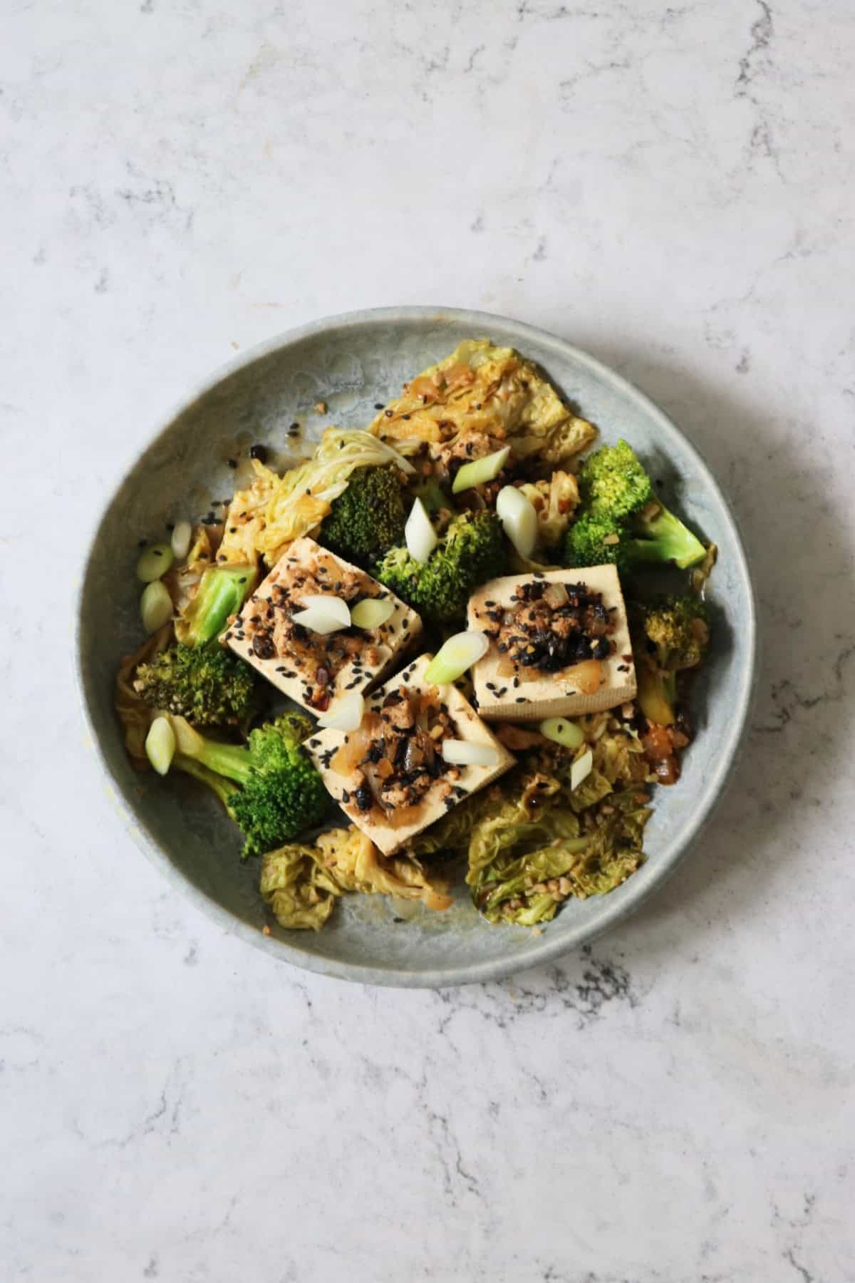 3 pieces of Braised Black Bean Stuffed Tofu served with cabbage and broccoli on a plate