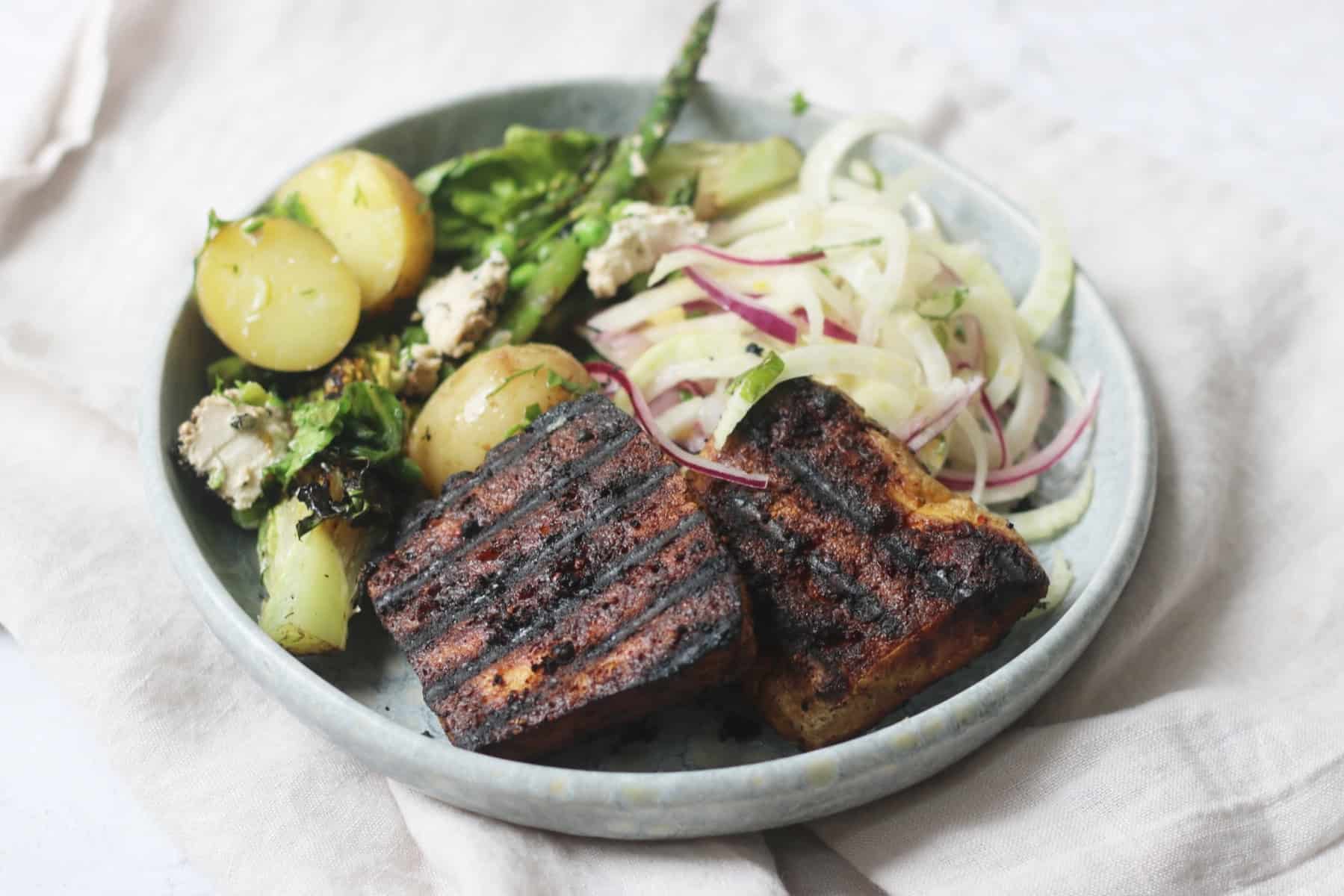 Vegan BBQ Tofu Steaks served on a light blue plate with salad.