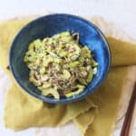 A bowl of Cold Sesame and Peanut Soba Noodles served with a green napkin and two wooden chopsticks