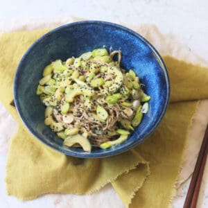 A bowl of Cold Sesame and Peanut Soba Noodles served with a green napkin and two wooden chopsticks