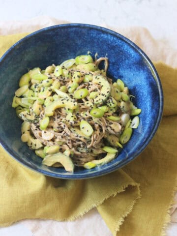 A bowl of Cold Sesame and Peanut Soba Noodles served with a green napkin and two wooden chopsticks