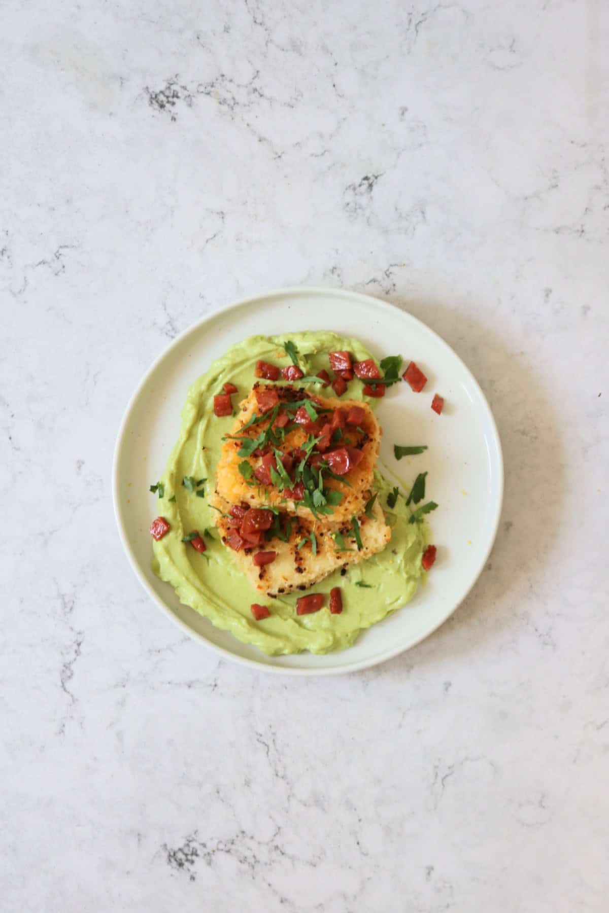 A plate of Crispy Lemon Pepper Tofu with Creamy Avocado Sauce and Bacon Crunch with fresh parsley.