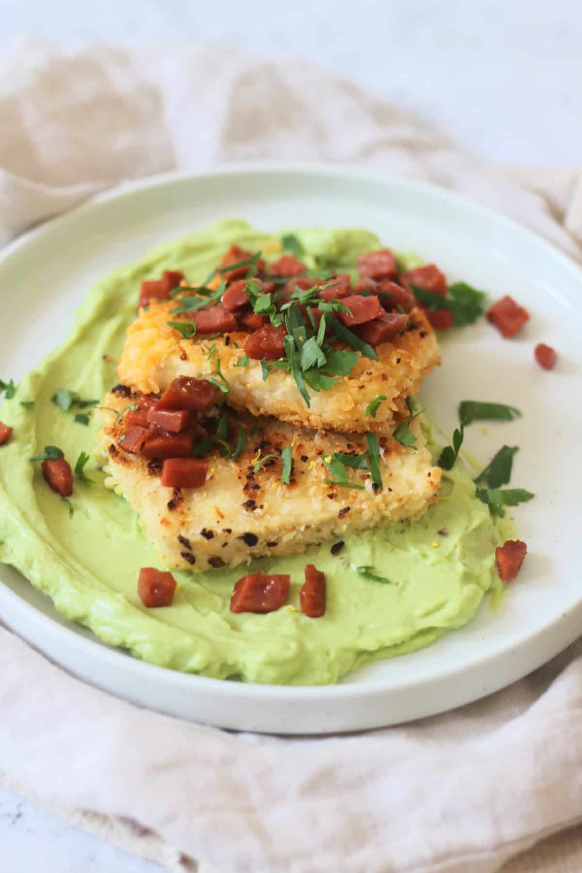 A plate of Crispy Lemon Pepper Tofu with Creamy Avocado Sauce and Bacon Crunch with fresh parsley.