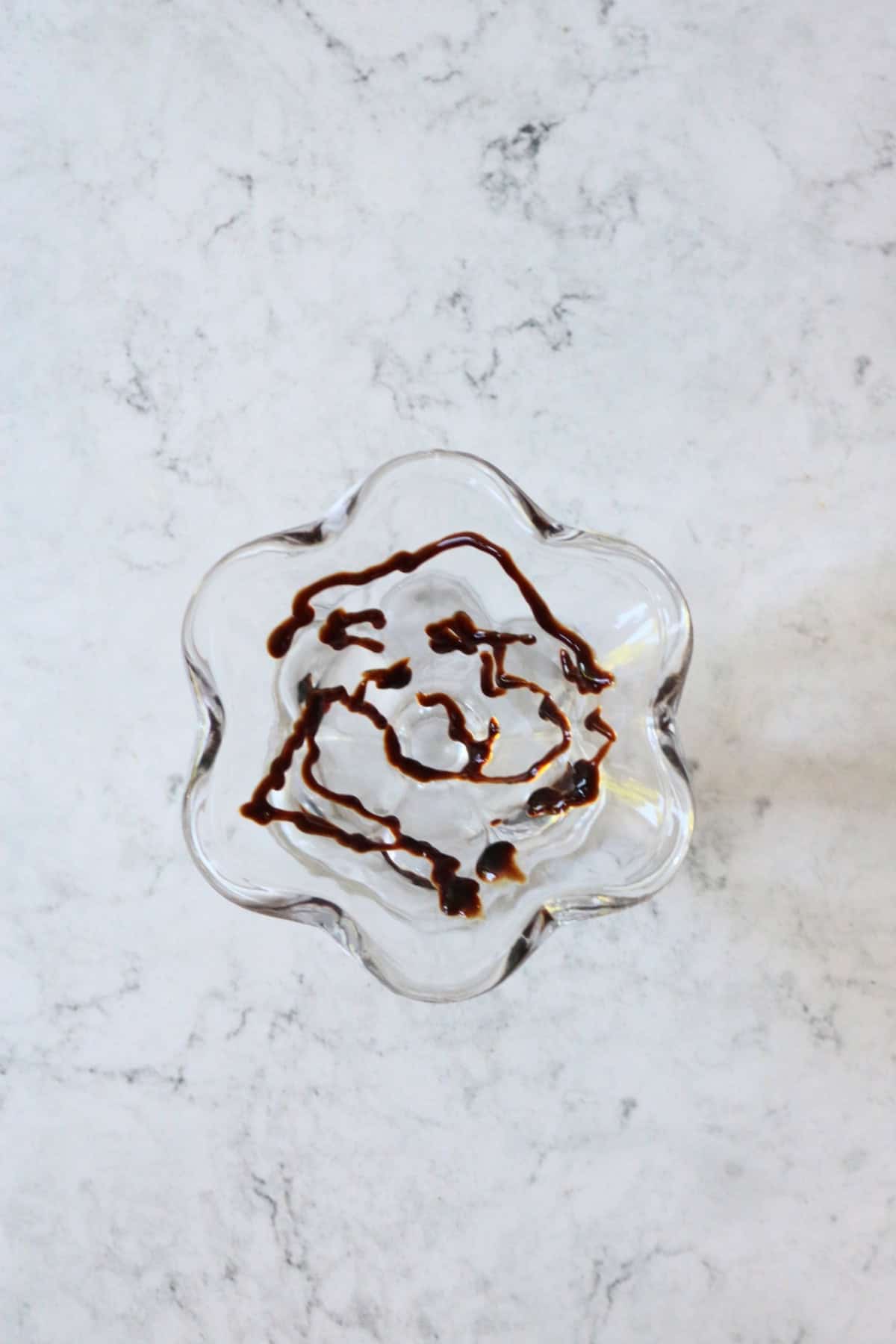 Balsamic glaze drizzled around the edges of an ice cream sundae glass