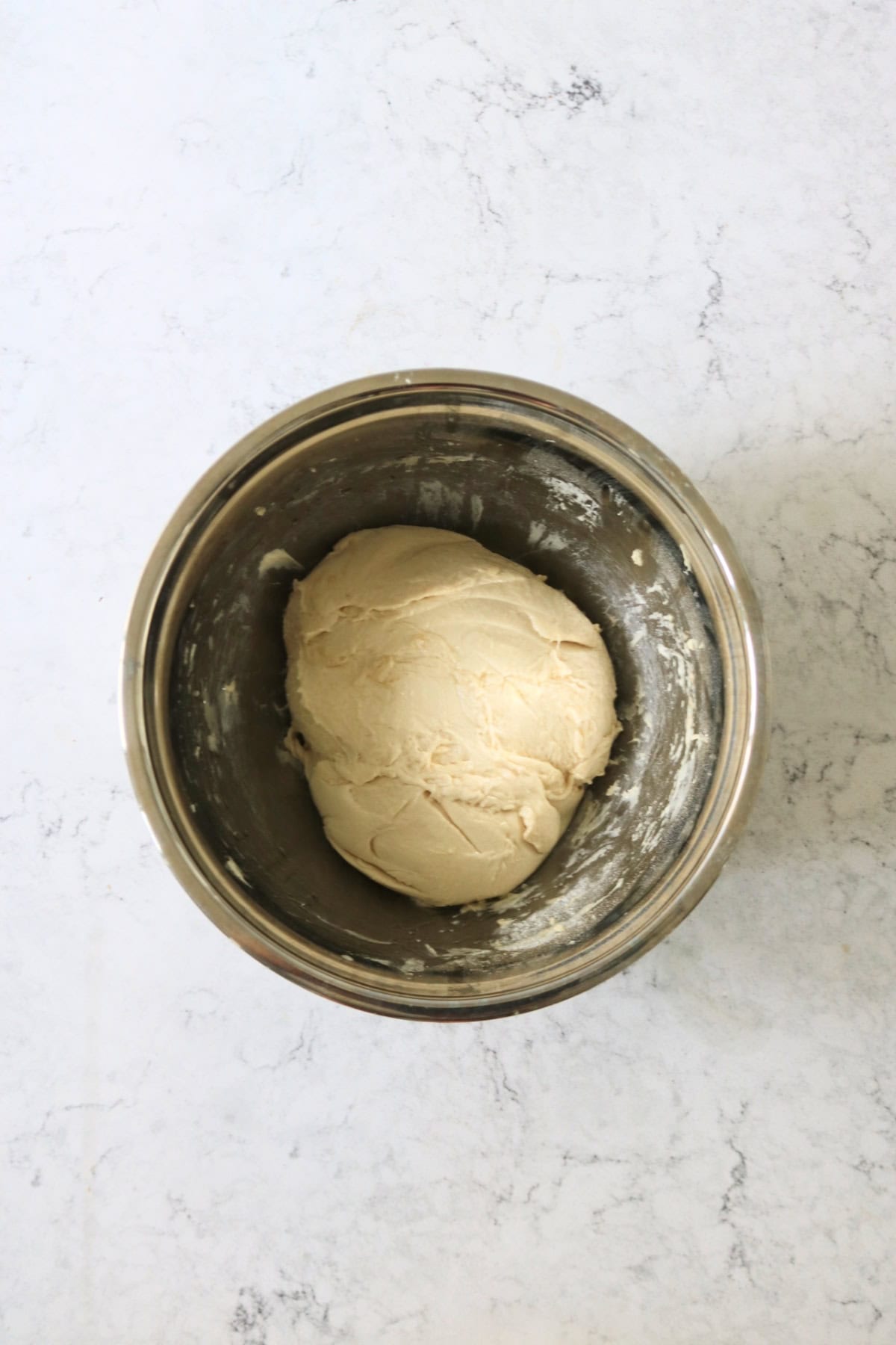 A ball of focaccia dough in a metal mixing bowl ready for its first prove