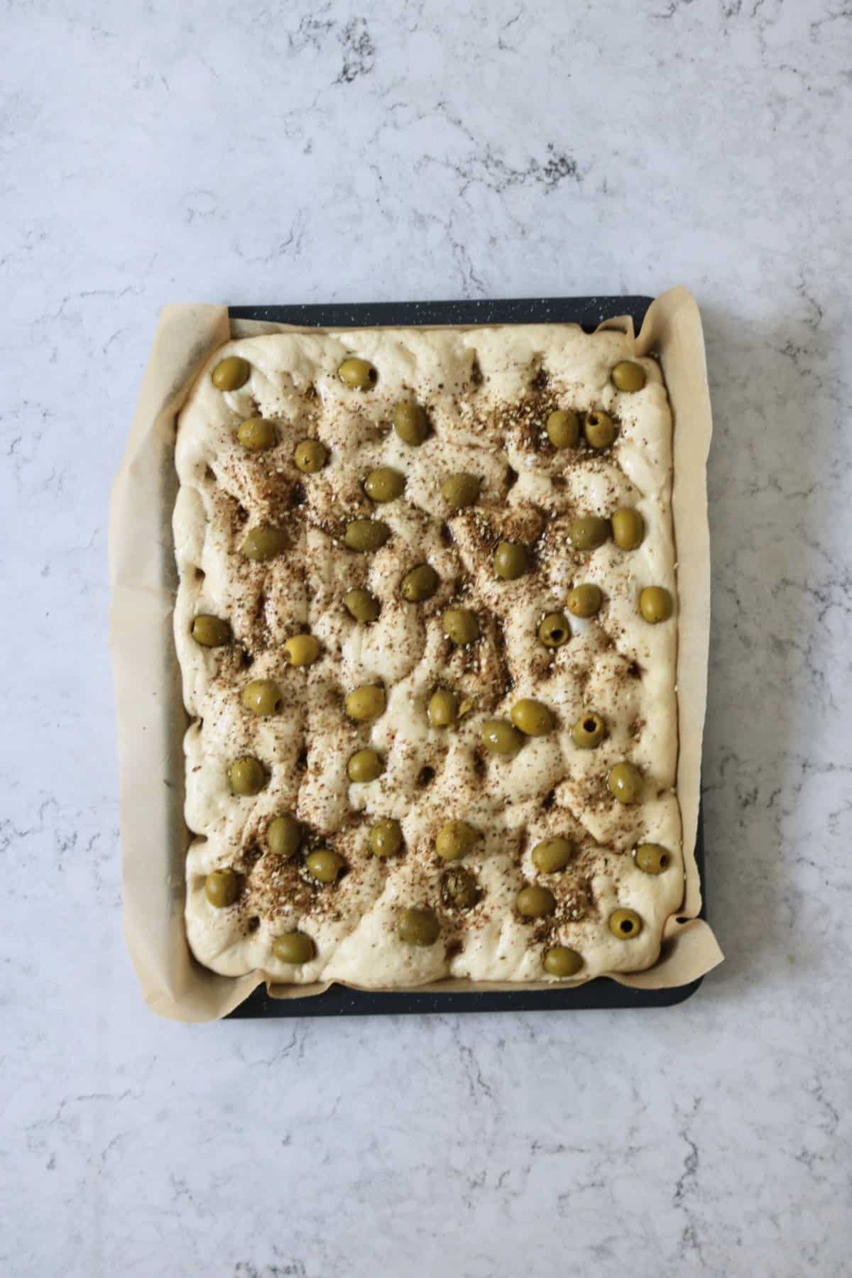Green Olive and Za'atar Focaccia on a baking tray ready for the oven