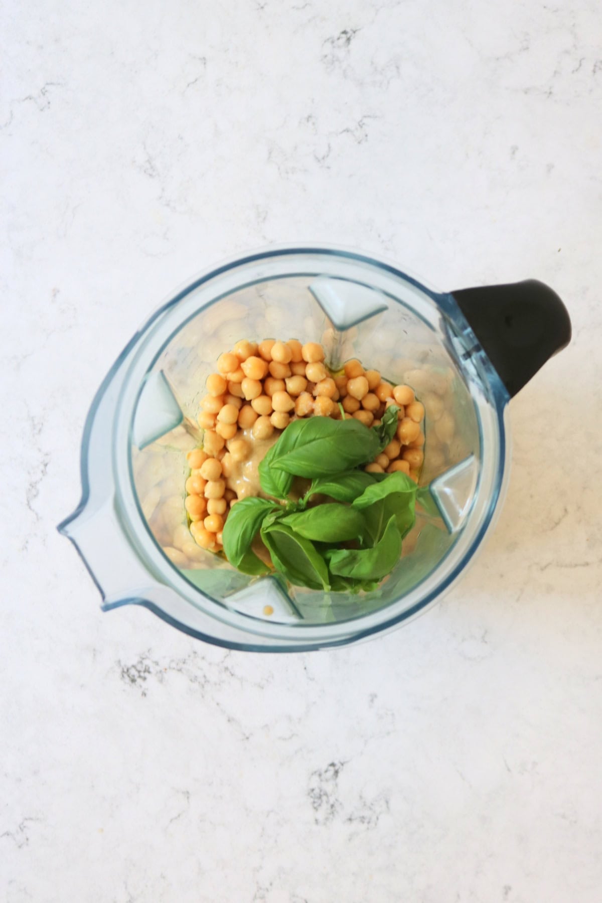 Chickpeas, lemon juice, olive oil, salt, basil leaves, roasted garlic gloves and tahini in a blender
