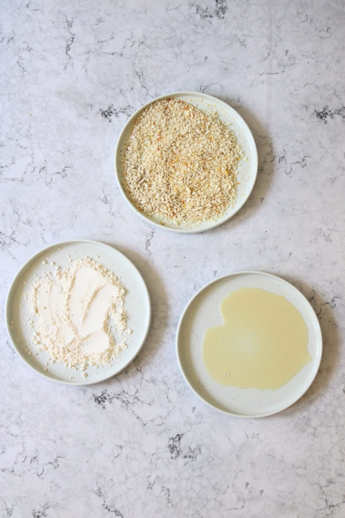3 plates, one with plant milk, one with flour and one with lemon-pepper breadcrumbs to be used to coat slices of tofu.