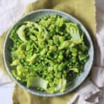 Pea and Broad Bean Salad with Little Gem Lettuce and Fresh Mint dressed with Dijon Mustard Dressing served on a light blue plate on top of a green napkin.