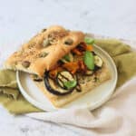 A Roasted Vegetable and Chickpea Focaccia Sandwich with the top slice of bread slightly askew showing the filling underneath