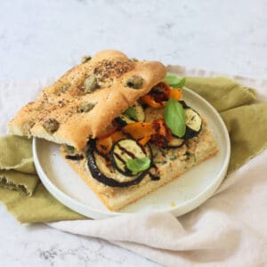 A Roasted Vegetable and Chickpea Focaccia Sandwich with the top slice of bread slightly askew showing the filling underneath