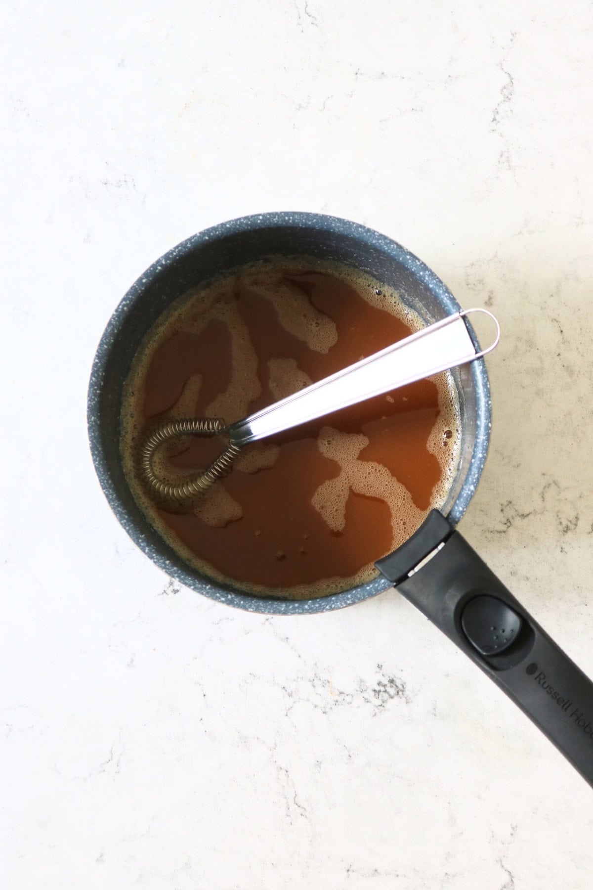Sichuan aubergine sauce in a small sauce pan with a sauce whisk