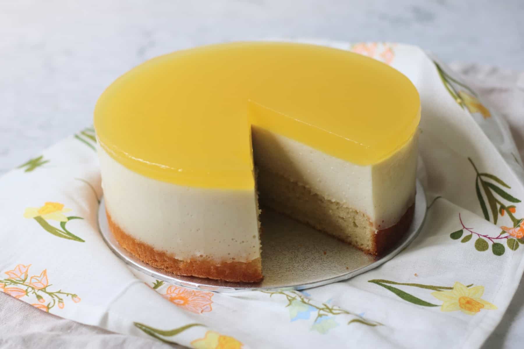 A Vegan White Chocolate and Lemon Mousse Cake with a large slice cut out of it.