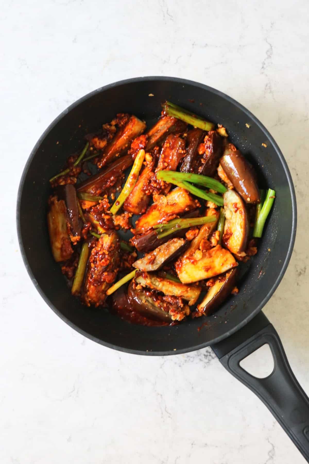 Stir fried Sichuan aubergines and spring onions in a large flat bottomed frying pan