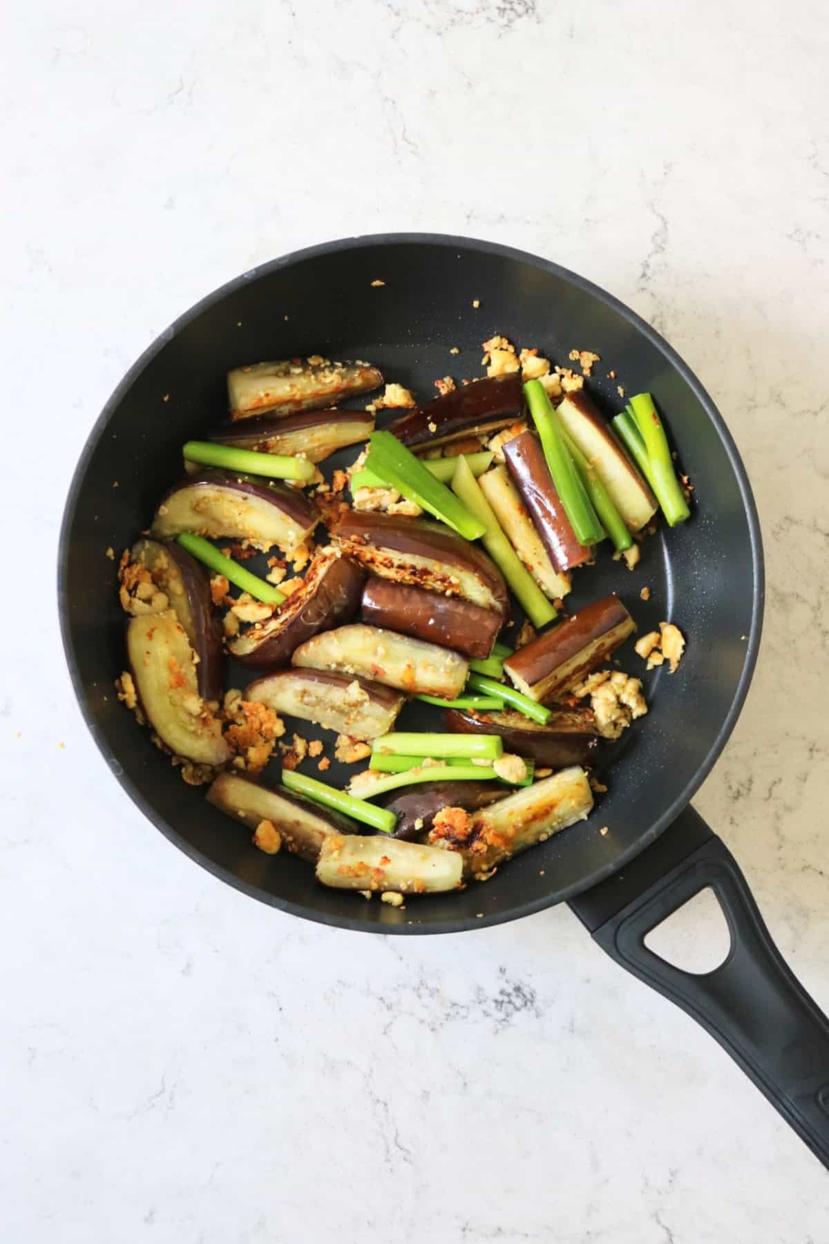 Stir fried aubergines and spring onions in a large flat bottomed frying pan