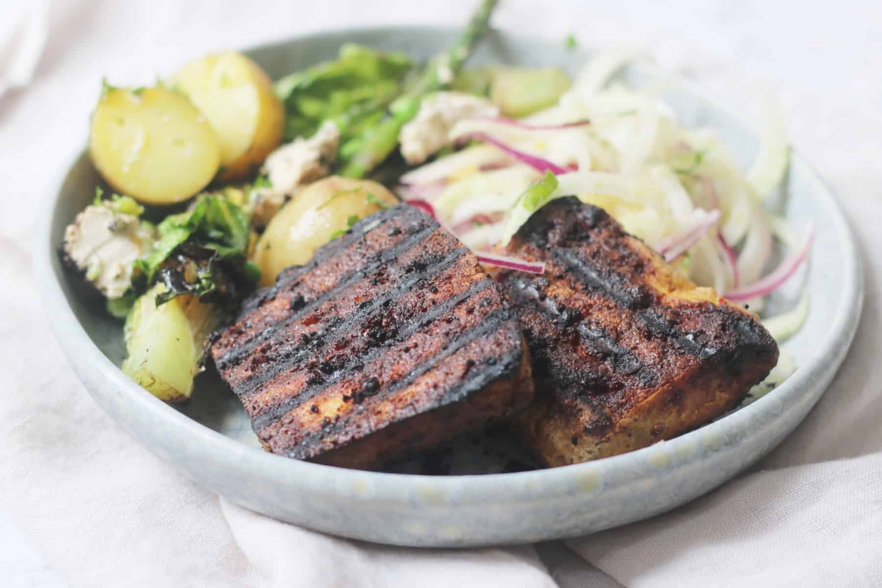 Vegan BBQ Tofu Steaks served on a light blue plate with salad.