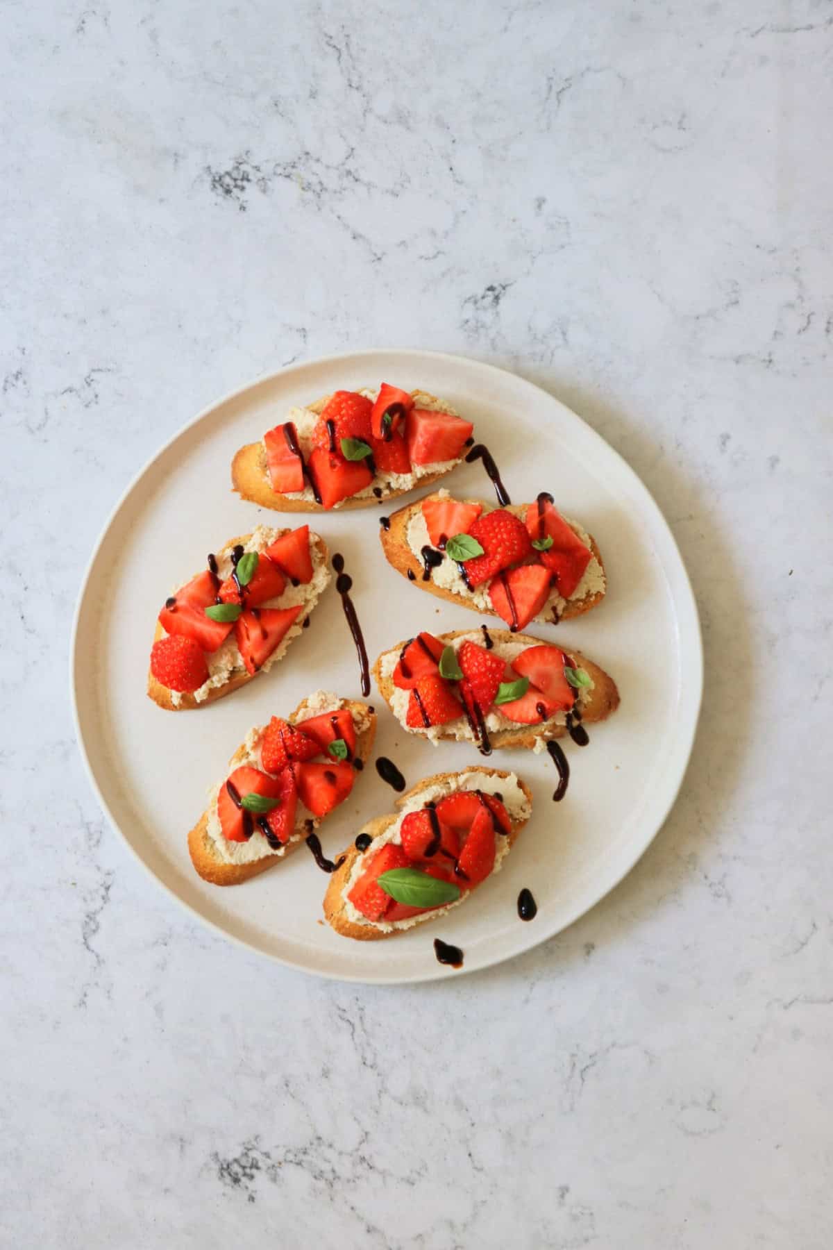6 Vegan Ricotta and Strawberry Crostini served on a white plate.