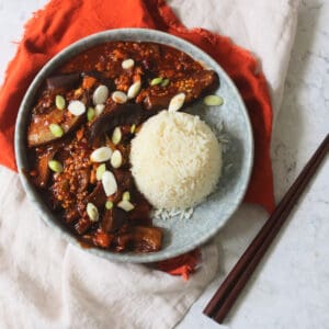 Vegan Sichuan Style Braised Aubergines topped with sliced spring onions and served with white rice