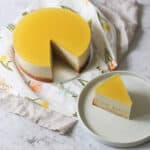 A Vegan White Chocolate and Lemon Mousse Cake with a slice cut out of it, served on a white side plate.