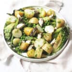 A large plate of BBQ Charred Lettuce Salad with Pepper-Crusted Vegan Goat's Cheese, New Potatoes & Asparagus on a white napkin
