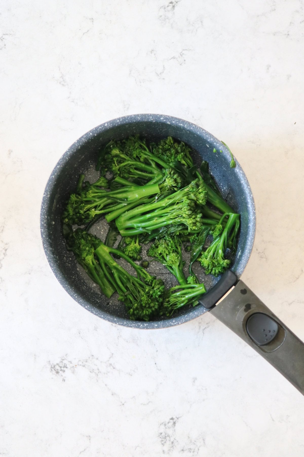 Tenderstem broccoli that has been cooked and then cooled in a pan