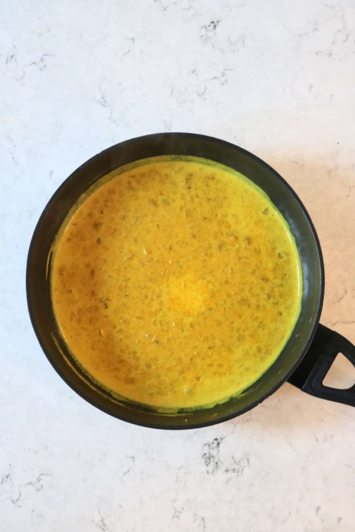 The sauce for Vegan Fish Balls simmering in a large, flat bottomed frying pan