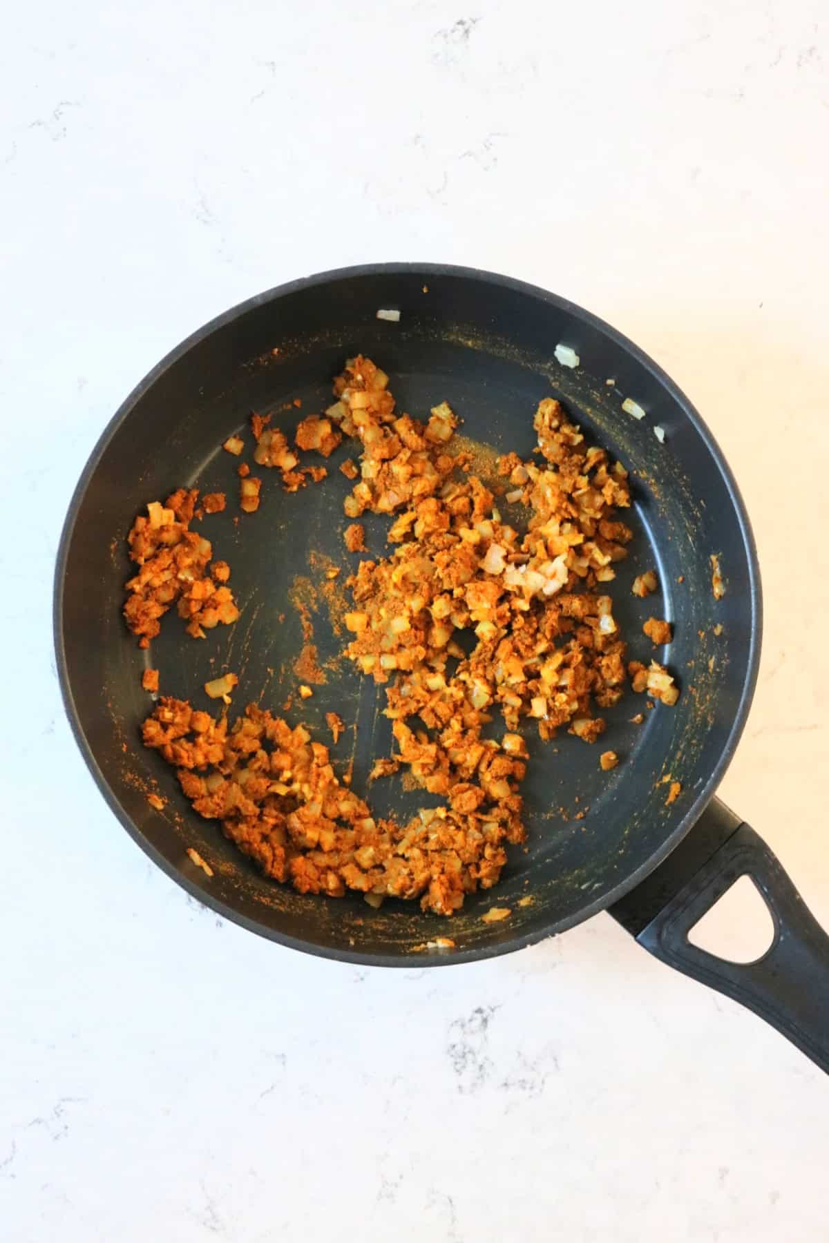 Onions and spices frying in a large, flat bottomed frying pan making the base of the sauce for Hong Kong Style Vegan Fish Balls