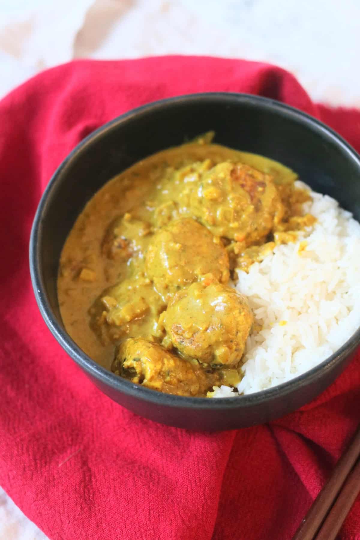 Hong Kong Style Vegan Curry Fish Balls served with white rice in a black bowl with a red napkin