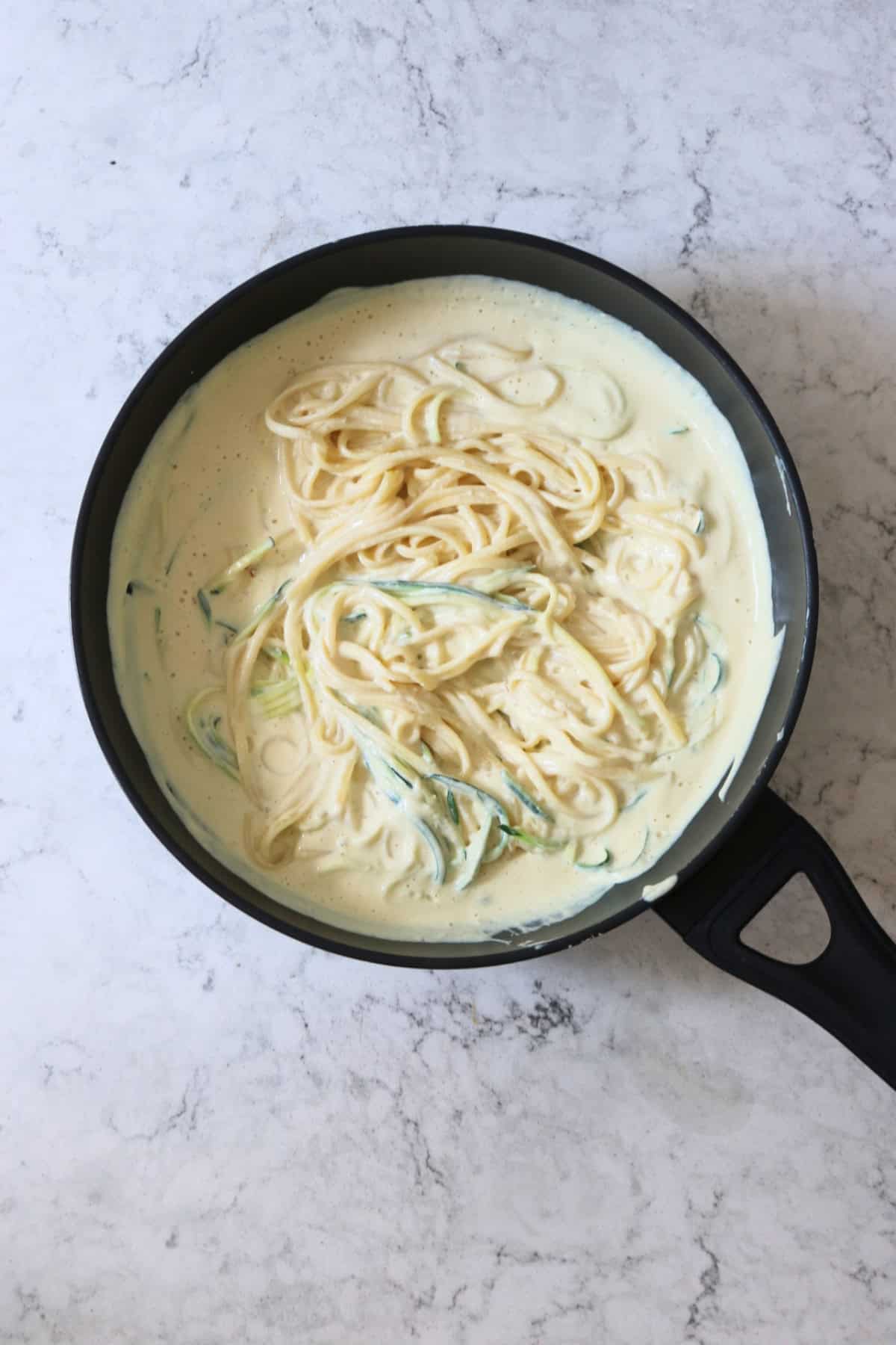 Vegan Creamy Courgette Linguine cooking in a large flat bottomed frying pan