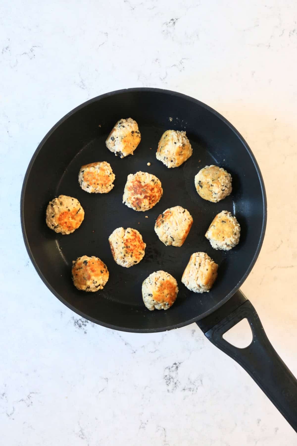 Vegan Fish Balls frying in a large, flat bottomed frying pan.