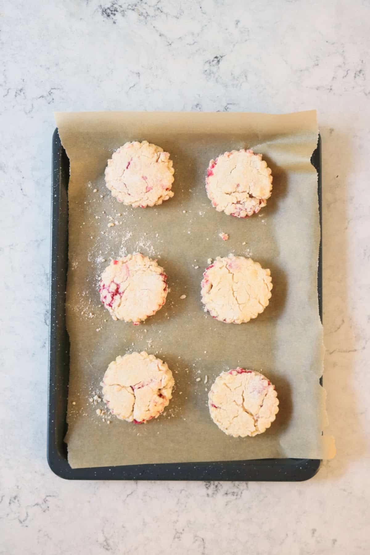 6 Vegan Raspberry and Lemon Scones on a baking tray, ready for the oven
