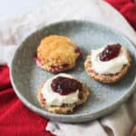 Vegan Raspberry and Lemon Scones on a plate topped with vegan cream and raspberry jam